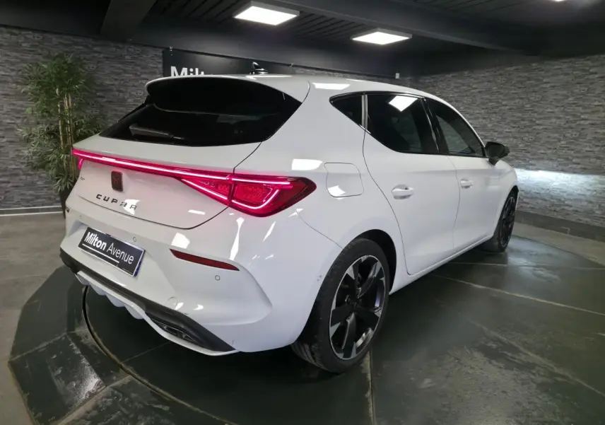 Vue 3/4 arrière droite d'une CUPRA Leon blanche Nevada avec feux arrière LED et jantes alliage noires.