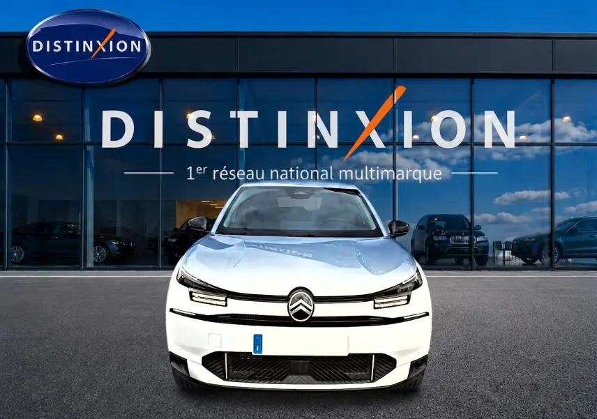 Vue frontale d'une Citroën C4 X blanche 2025 avec phares LED et calandre noire devant un bâtiment Distinxion.