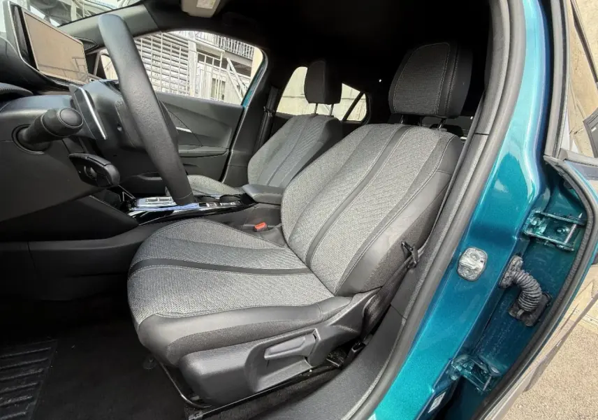 Vue intérieure côté conducteur du Peugeot 2008 2025 bleu obsession, mettant en valeur les sièges tissu et cuir gris et la console centrale.