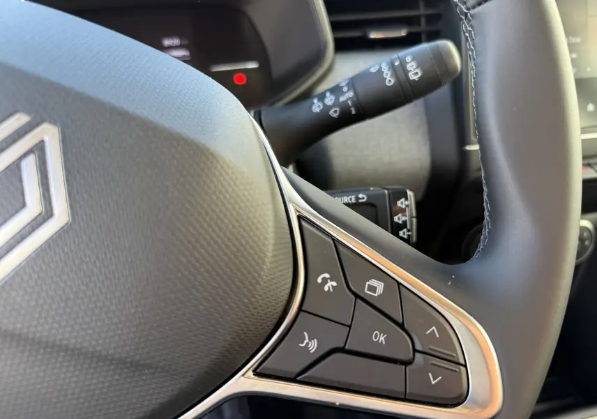 Gros plan sur le volant textile gainé de la Renault Clio V 1.5 dCi 100, avec commandes multifonctions visibles.