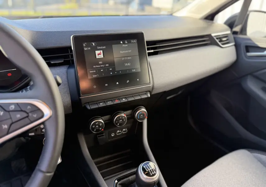 Vue intérieure du tableau de bord de la Renault Clio V gris schiste, avec écran tactile et levier de vitesses manuel.
