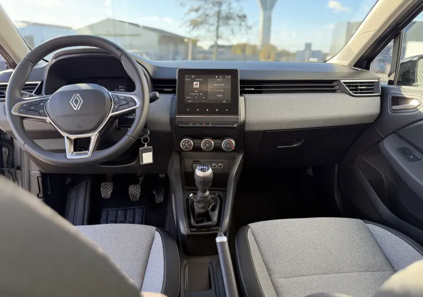 Intérieur de la Renault Clio V 1.5 dCi 100 gris schiste, vue frontale du tableau de bord avec volant et boîte manuelle.