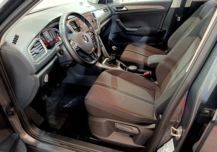 Intérieur avant droit du Volkswagen T-Roc gris foncé 2021, volant cuir, tableau de bord numérique et sièges tissu gris.