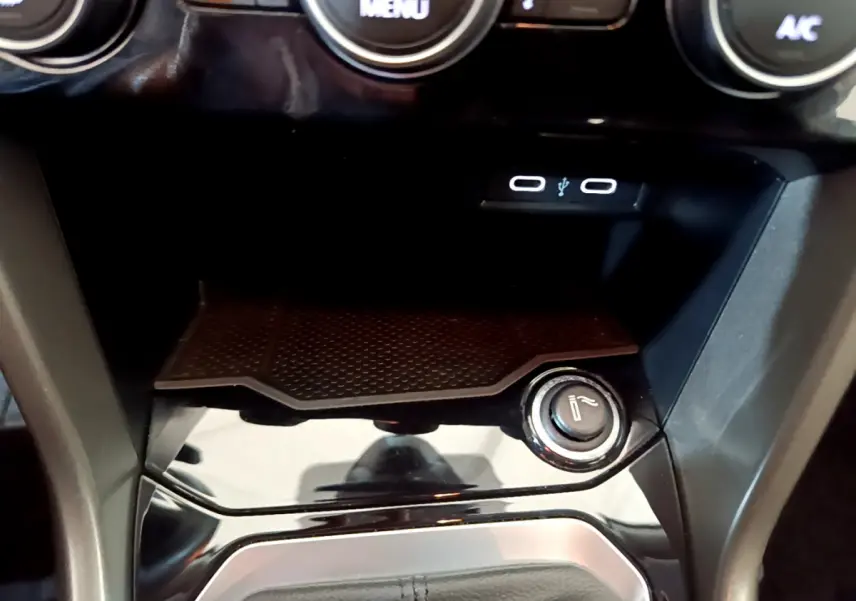 Gros plan sur la console centrale noire du Volkswagen T-Roc 2021, avec prise USB et allume-cigare visible.