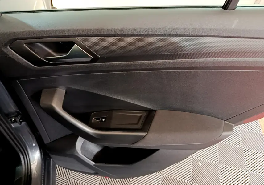 Vue rapprochée de la porte côté gauche du Volkswagen T-Roc gris foncé, mettant en valeur la poignée et les commandes de vitre.