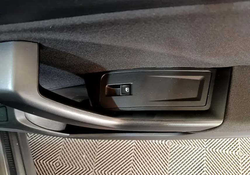 Poignée de porte intérieure côté conducteur du Volkswagen T-Roc gris foncé, avec bouton de verrouillage intégré.