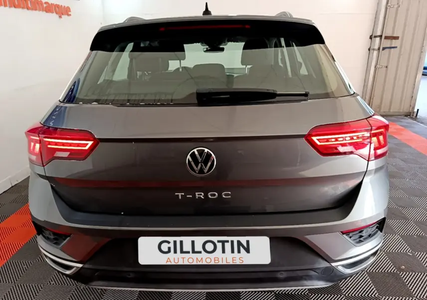 Vue arrière d'un Volkswagen T-Roc gris foncé avec feux LED allumés dans un showroom.