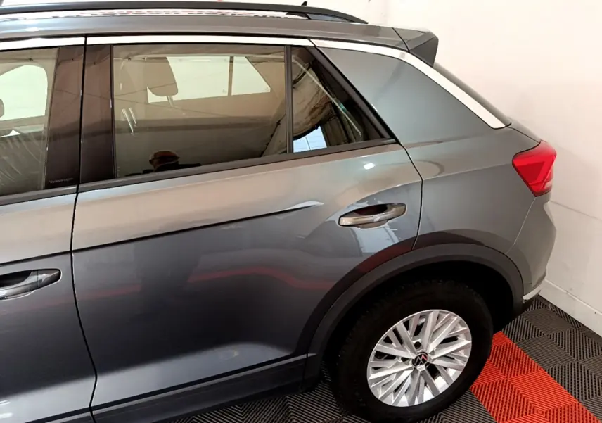 Vue côté droit arrière du Volkswagen T-Roc gris foncé 2021 avec jantes alliage et barres de toit noires.