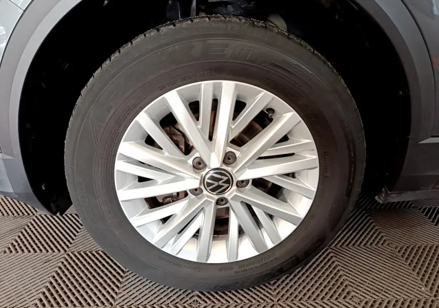 Gros plan sur la roue avant droite avec jante argentée et logo Volkswagen du T-Roc gris foncé 2021