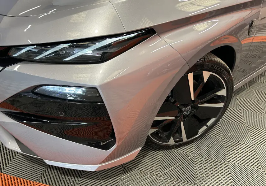 Gros plan sur l’avant droit gris Artense du Peugeot 308 III Ph.2 GT avec phares LED et jante noire et argent.
