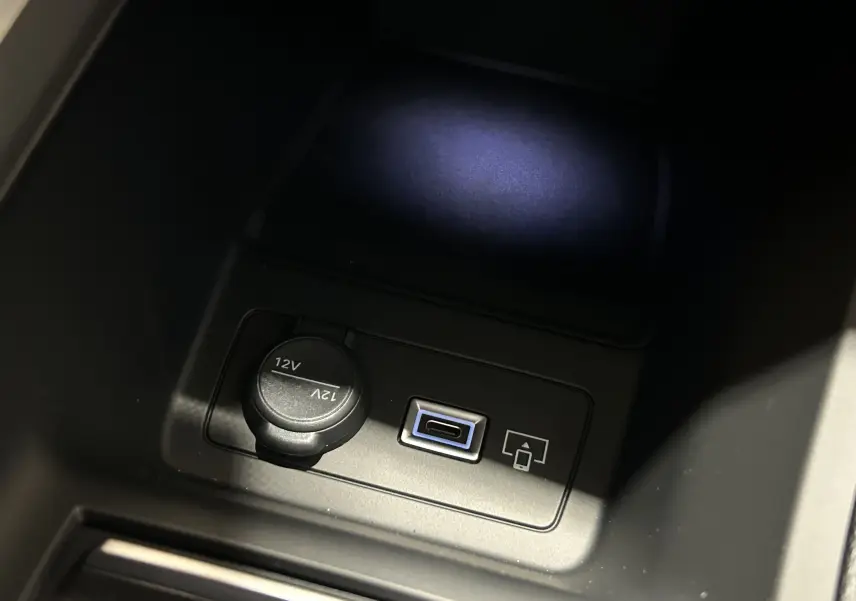 Gros plan intérieur sur la prise 12V et port USB-C du Peugeot 308 III Ph.2 GT Gris Artense, éclairage tamisé.