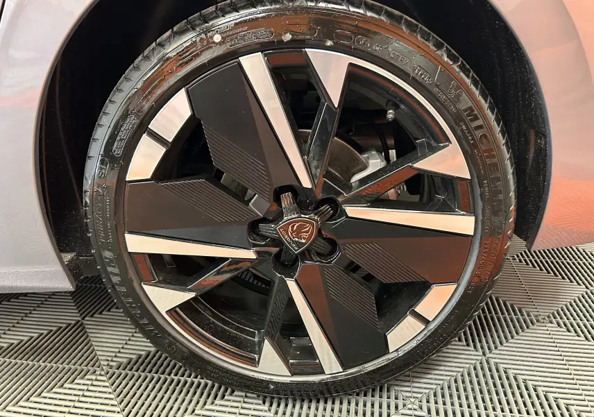 Gros plan sur la roue avant droite de la Peugeot 308 gris Artense, jante alliage noire et argentée au design moderne.