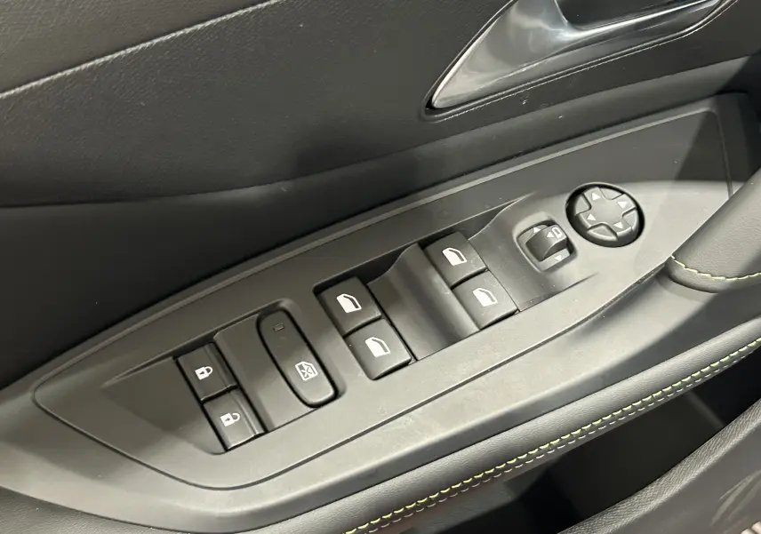 Gros plan sur les commandes de lève-vitres et rétroviseurs côté gauche intérieur d’une Peugeot 308 gris Artense.