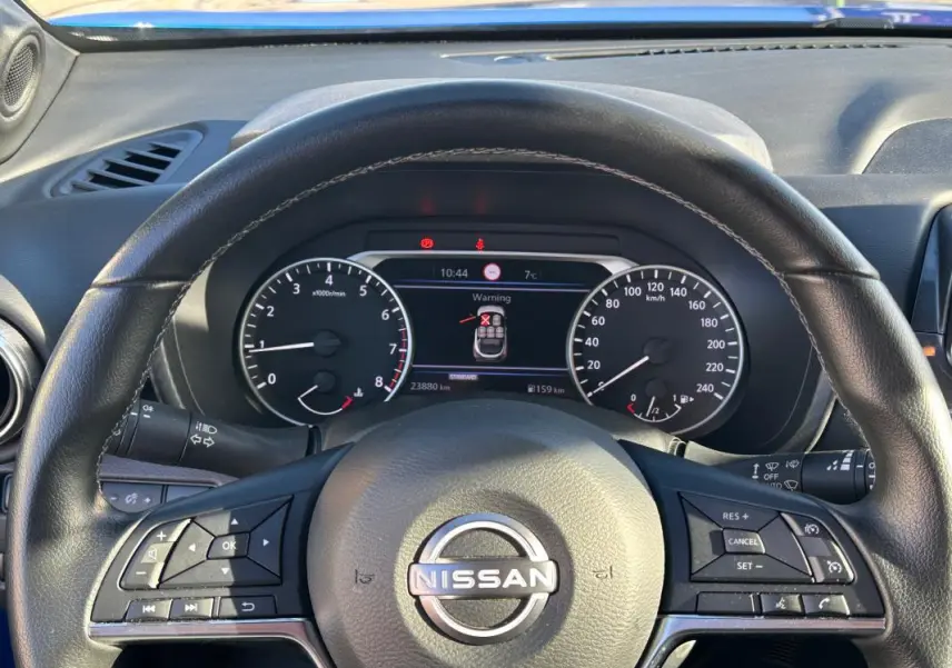 Vue rapprochée du volant noir d’un Nissan Juke 2024 avec tableau de bord numérique et commandes intégrées.