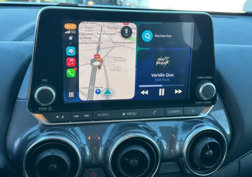 Écran tactile central du Nissan Juke 2023.5 DIG-T 114 Shadow avec navigation et musique, intérieur noir.