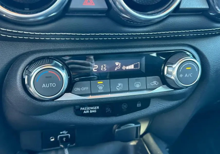 Gros plan sur la console de climatisation automatique du Nissan Juke 2023.5 bleu clair avec affichage digital et commandes rotatives.