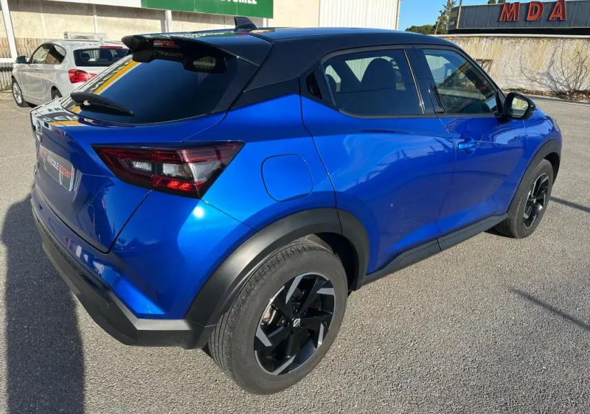 Vue 3/4 arrière droite du Nissan Juke 2024 bleu clair avec jantes alliage noires de 17 pouces et toit noir contrasté.