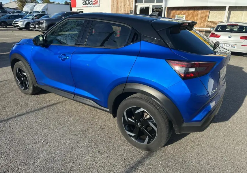 Nissan Juke 2024 bleu clair en vue 3/4 arrière droit, jantes alliage noires 17 pouces et toit noir contrasté.