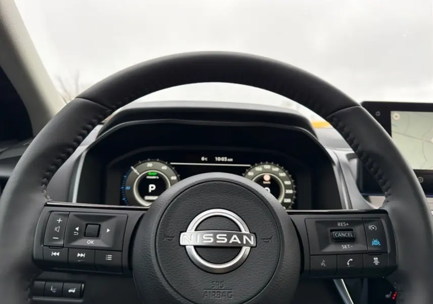 Vue rapprochée du volant cuir noir Nissan Qashqai 1.5 e-Power avec commandes multifonctions et tableau de bord numérique.