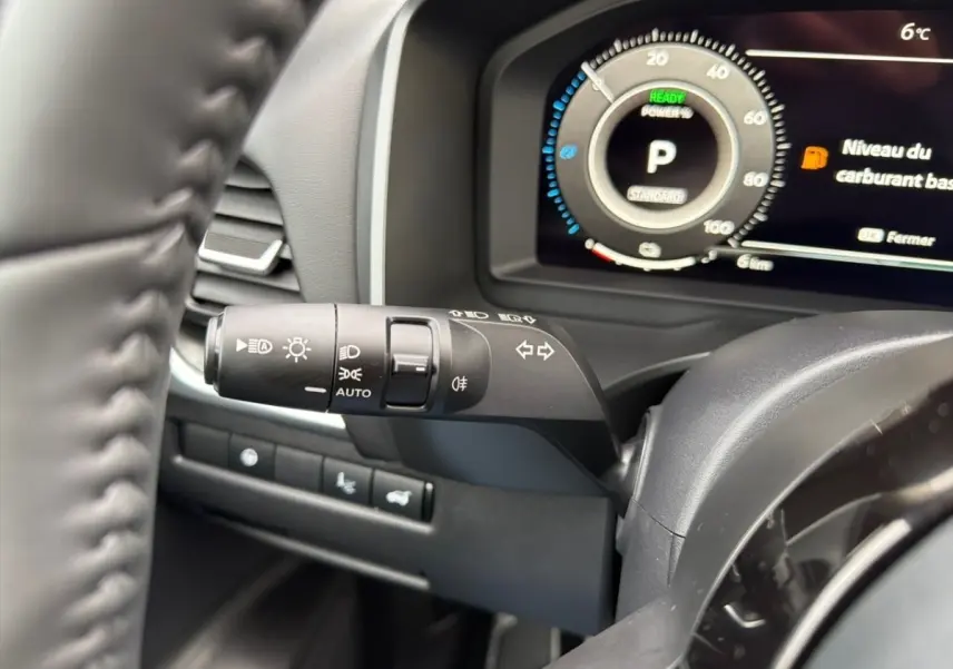 Gros plan sur le combiné d'instruments numérique et la commande des phares du Nissan Qashqai 1.5 e-Power noir, intérieur moderne.