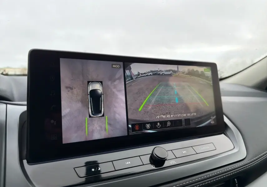 Écran tactile intérieur du Nissan Qashqai noir 2025 montrant la caméra 360° et l’aide au stationnement en vue arrière.