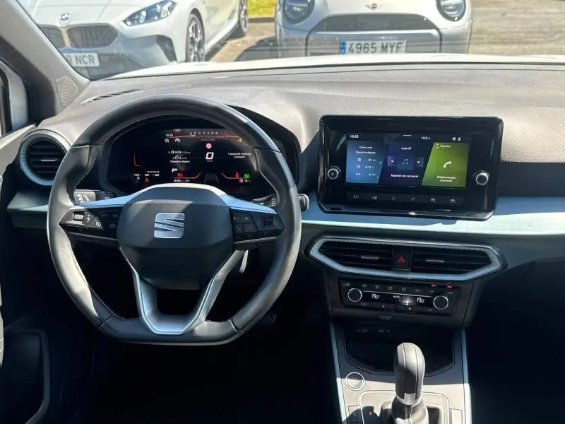 Vue intérieure frontale du tableau de bord et volant cuir noir du SEAT Arona 2025 avec écran tactile central allumé.