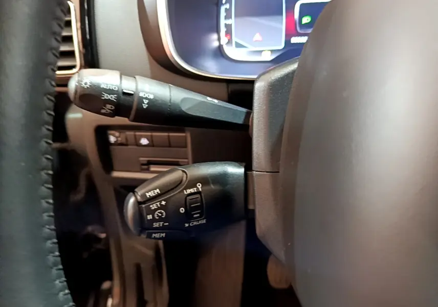 Gros plan sur les commandes au volant du Citroën C5 Aircross gris foncé, avec affichage numérique en arrière-plan.