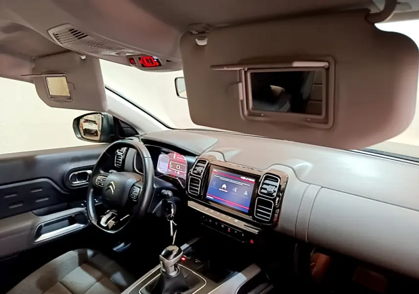 Intérieur du Citroën C5 Aircross 2020 vu côté conducteur, tableau de bord gris clair avec écran tactile et volant cuir noir.