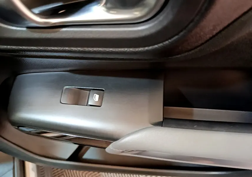 Gros plan sur la commande de lève-vitre côté gauche du Citroën C5 Aircross gris foncé, intérieur noir et gris.