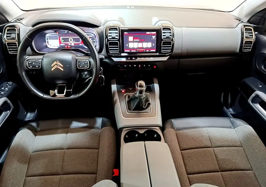 Vue intérieure avant du Citroën C5 Aircross 2020 montrant tableau de bord, volant cuir, écran tactile et sièges tissu gris.