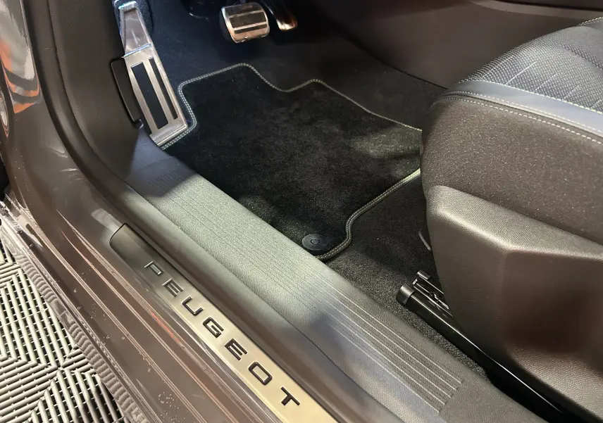 Vue rapprochée de la partie basse côté gauche d’une Peugeot 308 gris Selenium avec seuil de porte marqué PEUGEOT.
