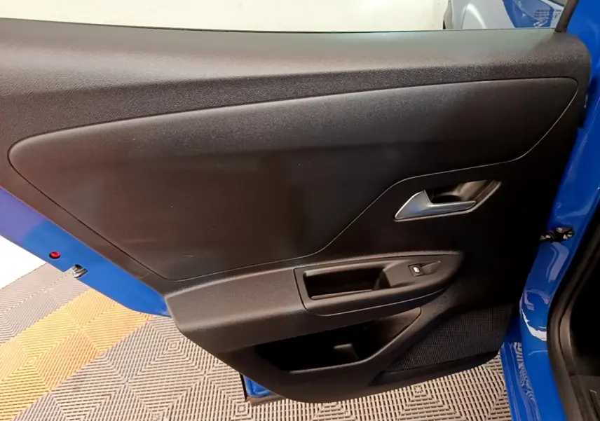 Vue rapprochée de la porte arrière gauche noire avec poignée argentée sur Opel Mokka bleu 2024.