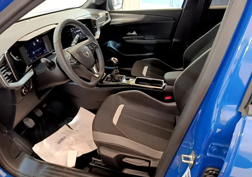 Vue intérieure côté conducteur de l’Opel Mokka bleu 2024, volant cuir, tableau de bord digital et boîte manuelle.