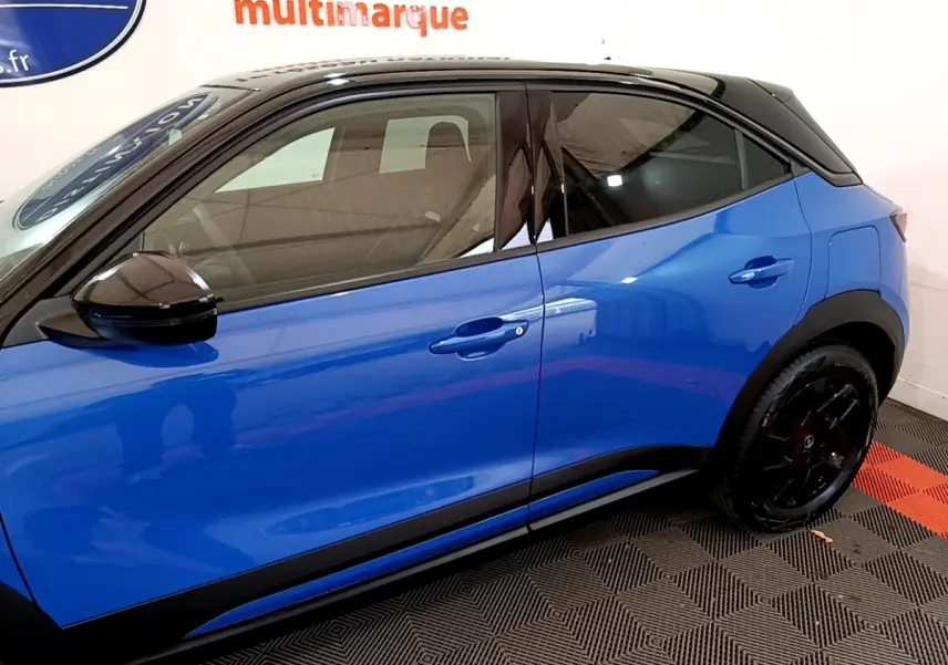 Profil droit d’un Opel Mokka 2024 bleu avec toit et rétroviseur noirs, jantes noires et poignées couleur carrosserie.