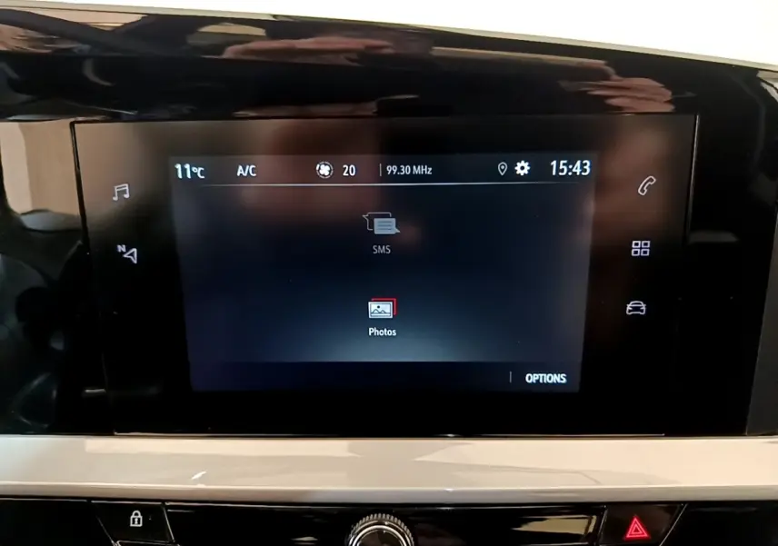 Écran tactile central de l’Opel Mokka 2024 affichant les options SMS et photos, avec commandes tactiles latérales visibles.