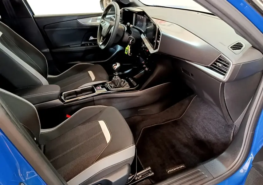 Intérieur avant droit de l’Opel Mokka bleu 2024, avec tableau de bord moderne et boîte manuelle visible.