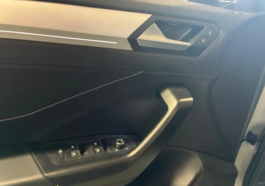 Intérieur côté gauche de la porte avant du Volkswagen T-Roc gris clair, avec commandes de vitres et serrure visibles.