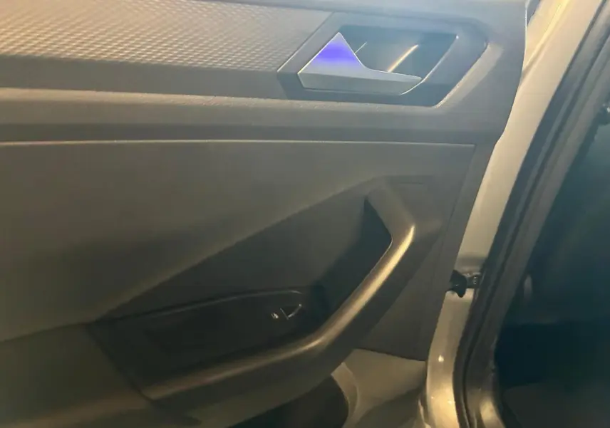 Détail de la porte intérieure côté gauche du Volkswagen T-Roc gris clair, avec poignée et commande de vitre.