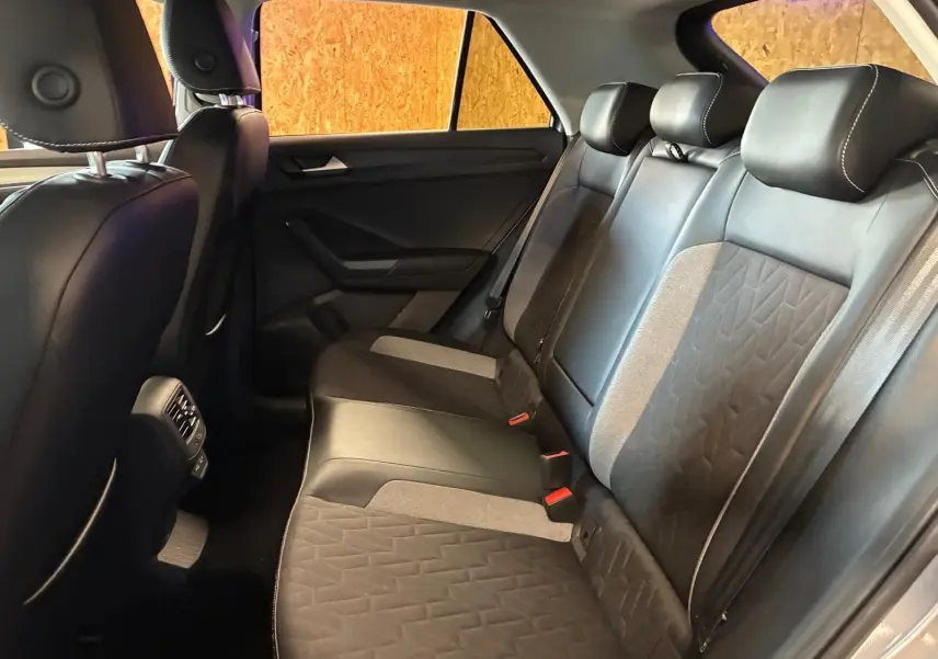 Vue intérieure arrière du Volkswagen T-Roc 2025 montrant les sièges en tissu noir et gris avec appuie-têtes et ceinture de sécurité.