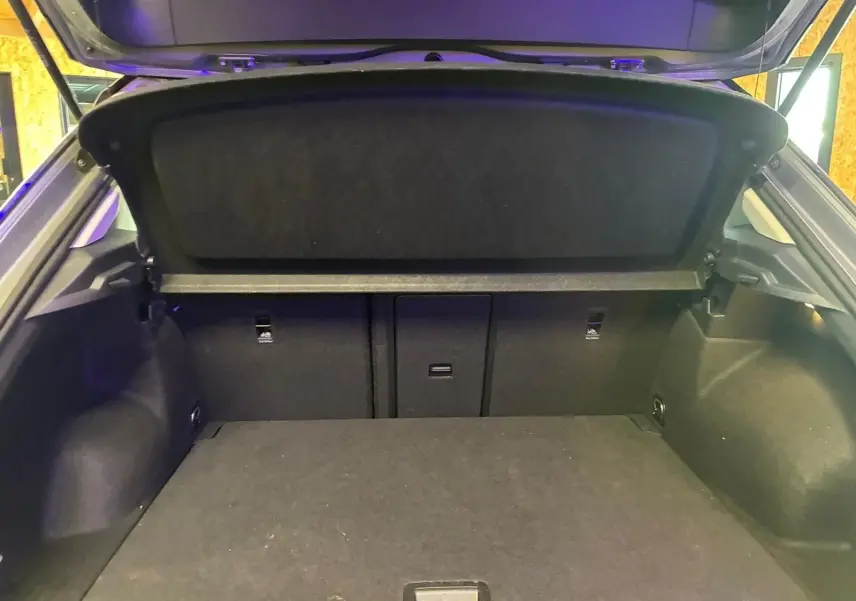 Coffre ouvert vu de l'arrière d'un Volkswagen T-Roc gris clair 2025, montrant l'espace de chargement et la plage arrière.