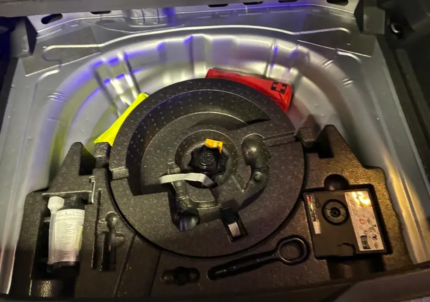Coffre ouvert montrant la roue de secours et les outils de bord du Volkswagen T-Roc gris clair, version 2025.