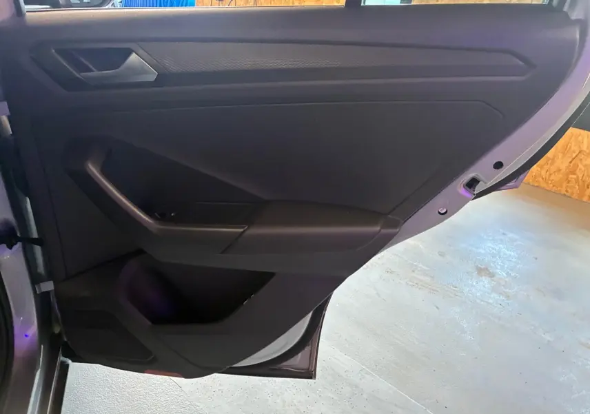 Vue rapprochée de la porte arrière droite du Volkswagen T-Roc gris clair, montrant les commandes et le rangement intérieur.