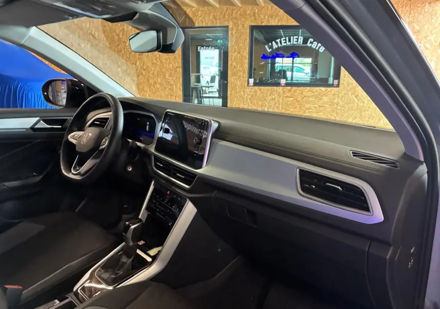 Vue intérieure côté conducteur du Volkswagen T-Roc 2025, mettant en valeur le tableau de bord moderne et l’écran tactile central.