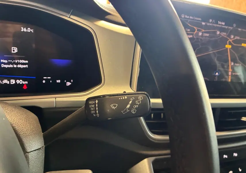 Gros plan sur le commodo d’essuie-glace du tableau de bord d’un Volkswagen T-Roc 2025 gris clair avec écran GPS visible.
