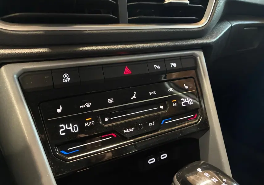 Gros plan sur la console centrale du Volkswagen T-Roc 2025 gris clair, mettant en valeur la climatisation digitale et le levier de vitesse automatique.