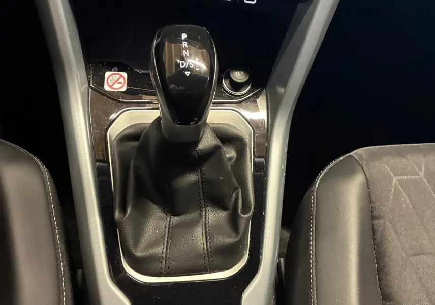 Gros plan sur la console centrale du Volkswagen T-Roc 2025, montrant le levier de vitesses automatique et la climatisation digitale.