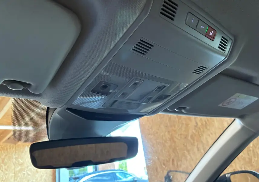 Vue intérieure du plafonnier et rétroviseur d’un Volkswagen T-Roc gris clair, avec commandes d’éclairage et toit clair.