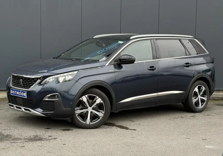 Peugeot 5008 bleu foncé en vue 3/4 avant droit, avec jantes alliage bi-ton et toit noir brillant.
