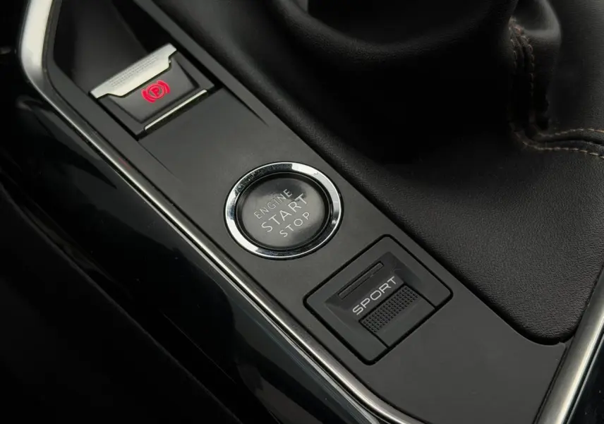 Gros plan sur la console centrale noire du Peugeot 5008 bleu foncé, avec bouton Start/Stop et mode Sport visible.
