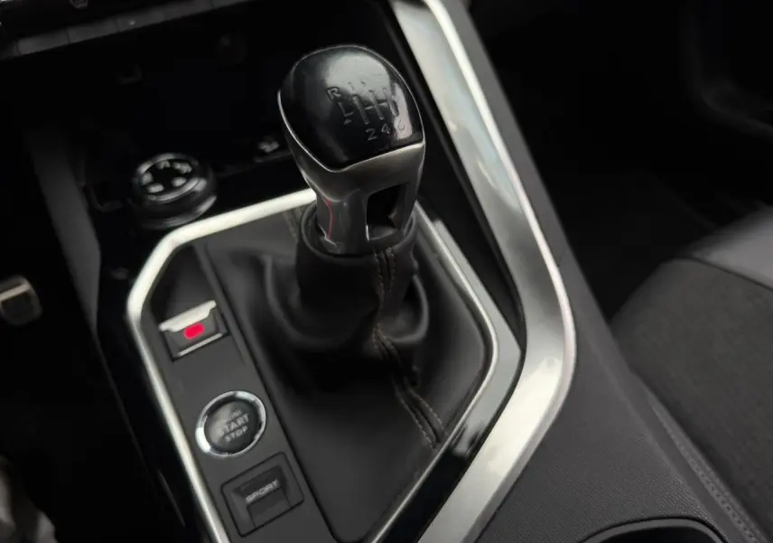 Gros plan sur le levier de vitesses manuel noir du Peugeot 5008 GT Line, entouré de commandes et console noire.